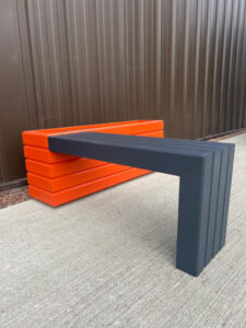 dark grey wooden bench attached to an orange wooden planter