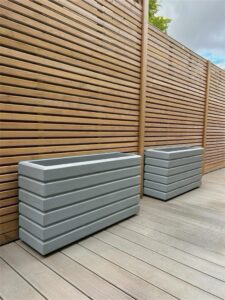 Light grey planters against a natural wooden trellis