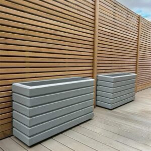 Light grey planters against a natural wooden trellis