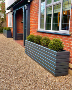 dark grey planter against a red brick house wall