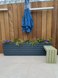 sage green wooden bench attached to a dark grey wooden planter