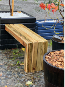 natural wood bench attached to a small square planter