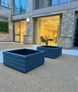 pair of dark grey square planters on a gravel surface