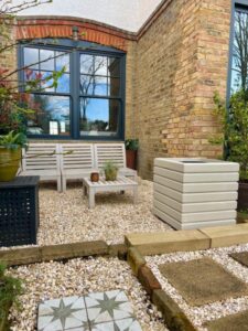 light natural wood coloured square planter outside in a small gravelled garden