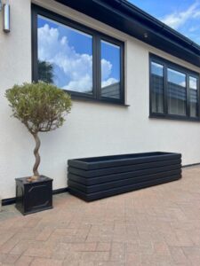 dark grey wooden planter against a white building