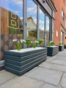 dark grey wooden planters with small plants inside against a glass window