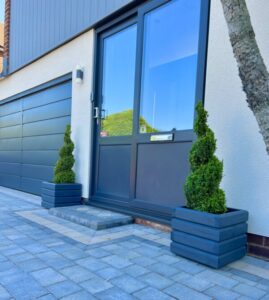 pair of dark grey square planters either side of a metal front door